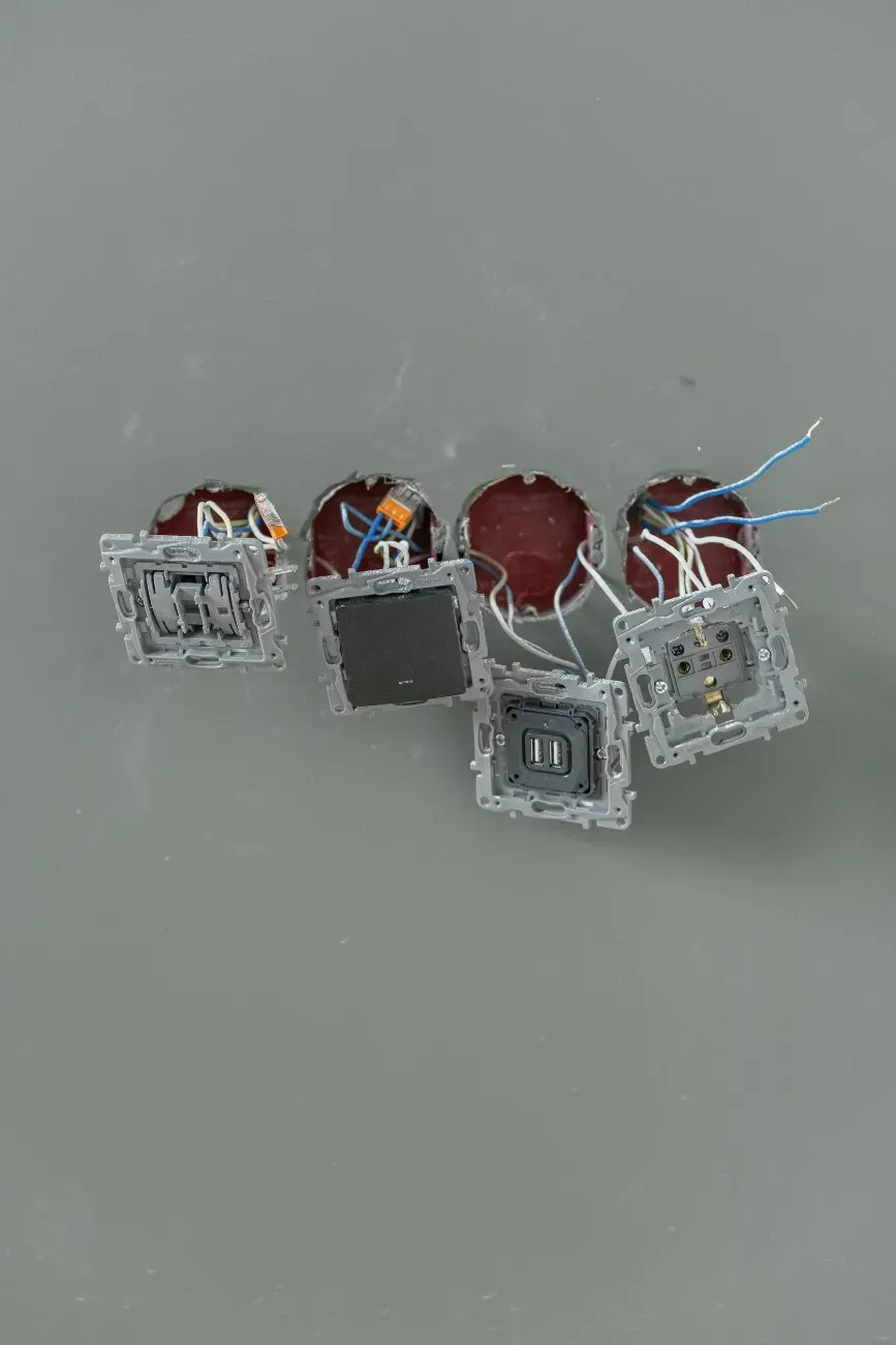 Tomas de corriente y cables eléctricos en pared gris.