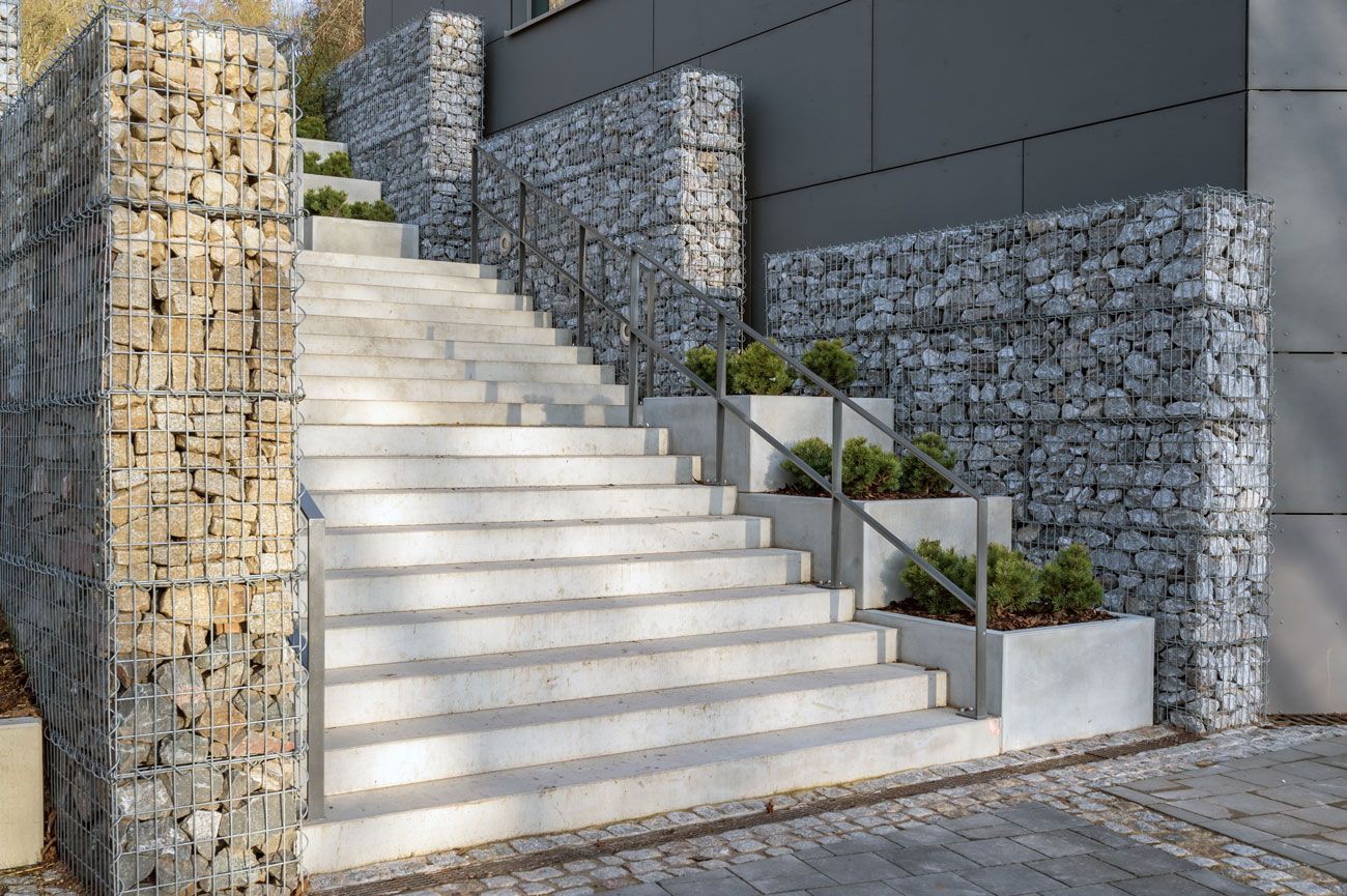 Eine Treppe führt zu einem Gebäude neben einer Steinmauer hinauf.