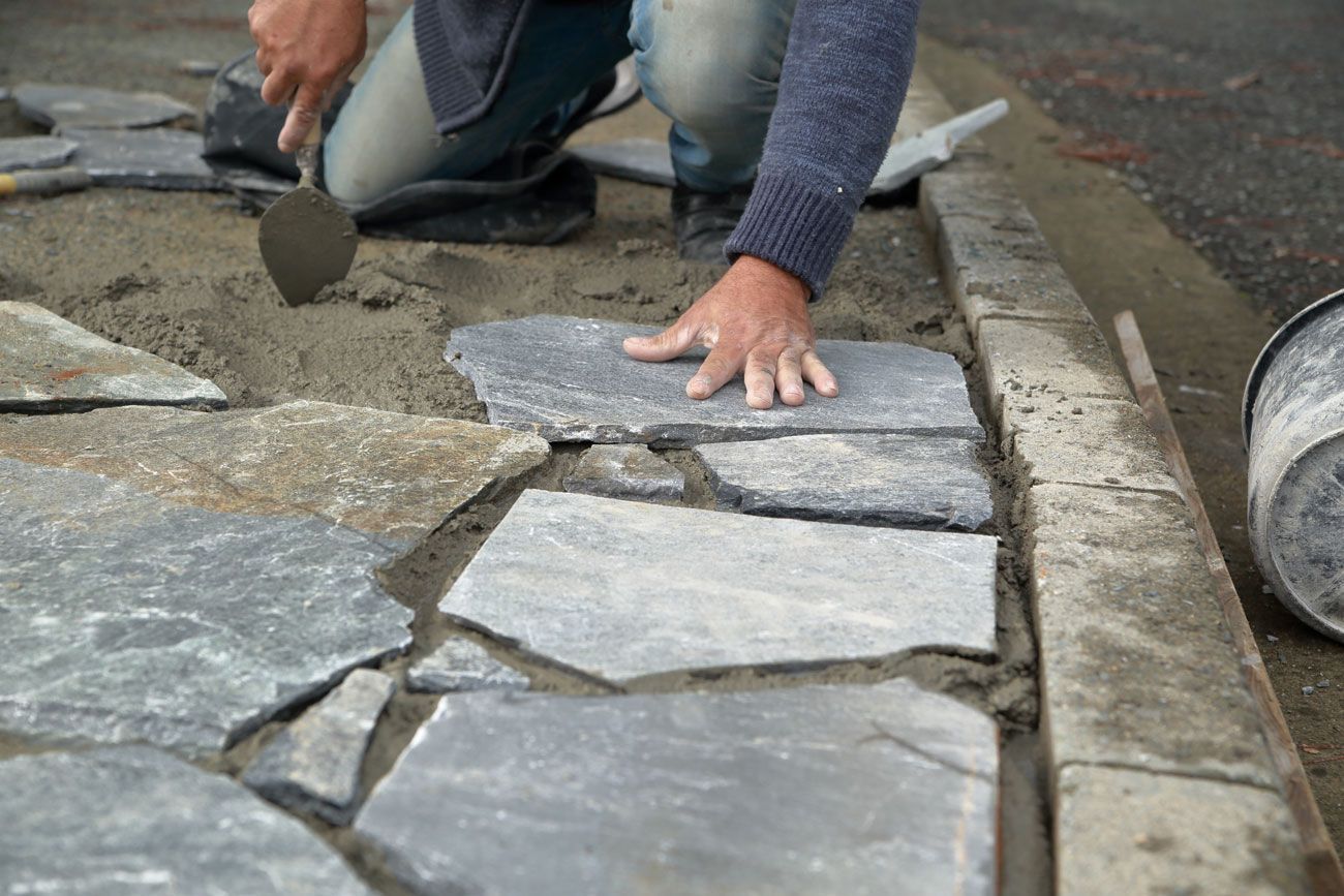 Ein Mann verlegt einen Steinweg.