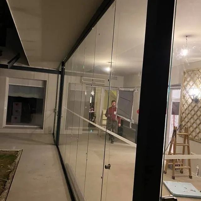 Un hombre está de pie en una habitación detrás de una pared de cristal.