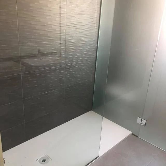 Un baño con ducha a ras de suelo y puerta de cristal.