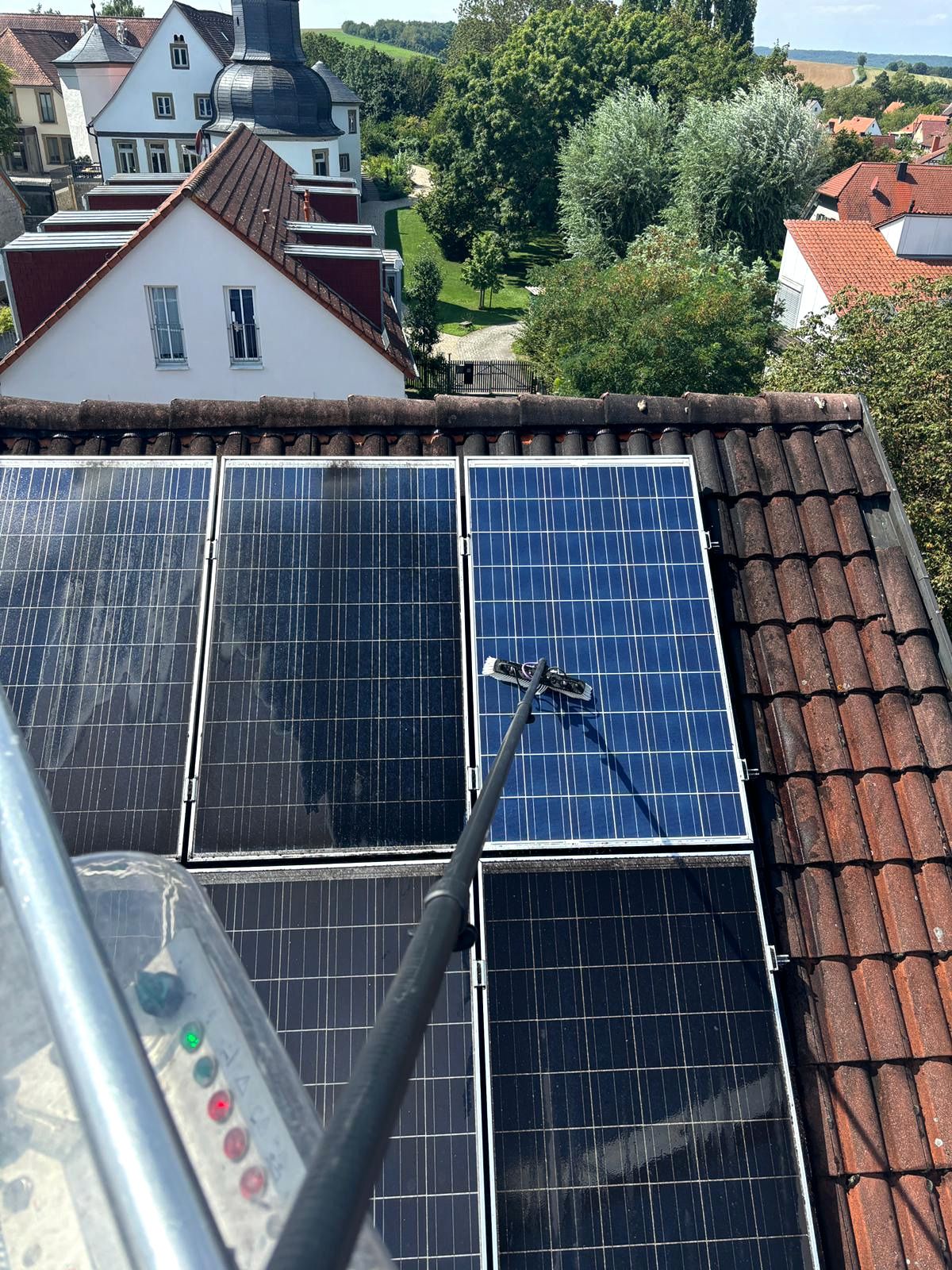 Solarpaneele auf einem Ziegeldach in einem Wohngebiet unter hellem Sonnenlicht.