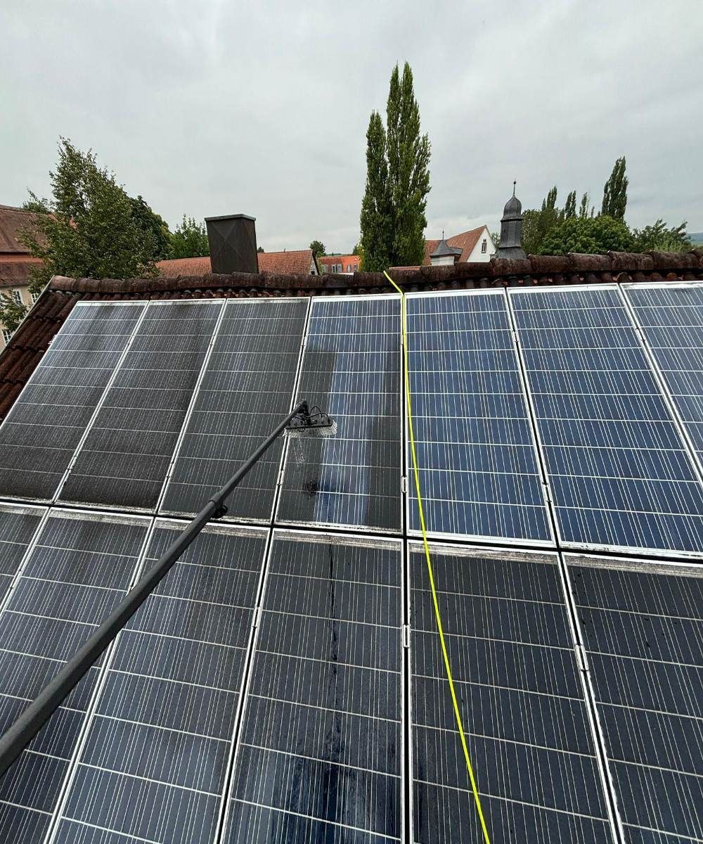 Solarpaneele auf einem Dach unter bedecktem Himmel, über die Kabel verlaufen.
