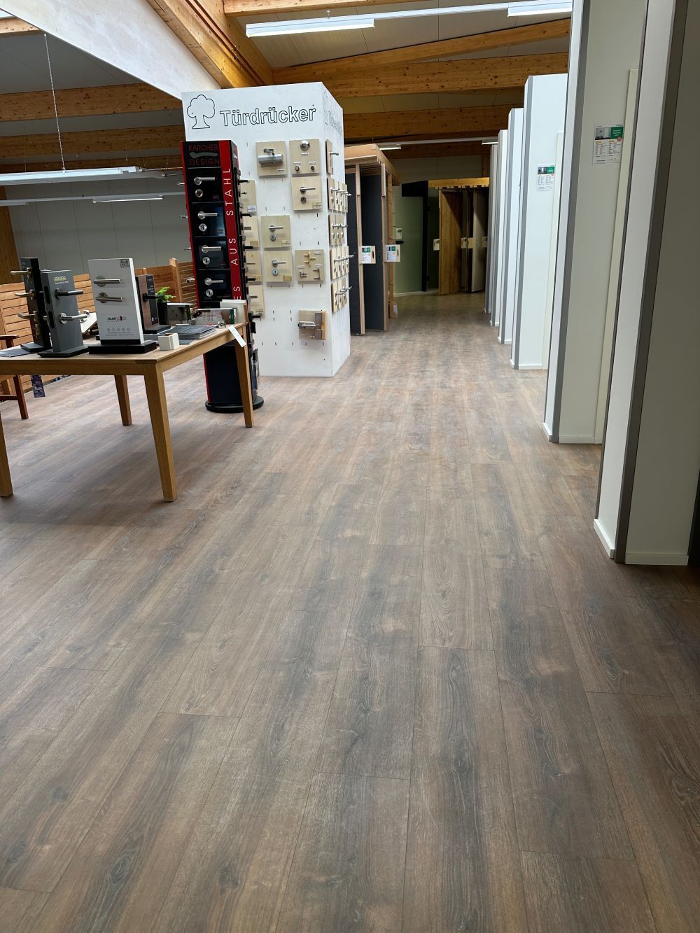 Moderne Bürolobby mit Holzboden, Ausstellungsregalen und einem Tisch auf der linken Seite.