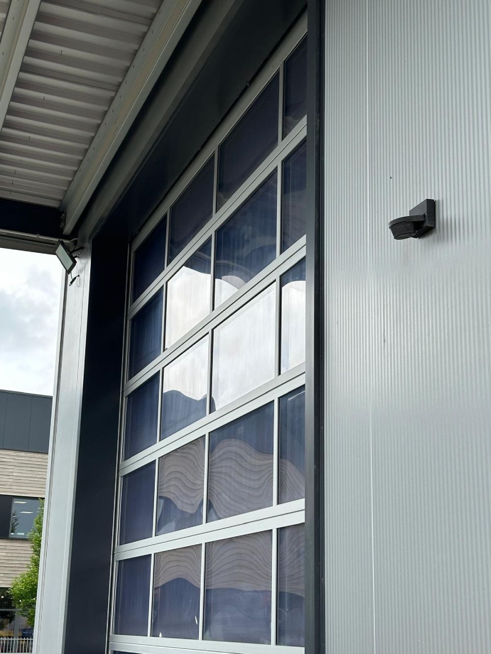 Fassade eines Industriegebäudes mit großen, reflektierenden Glasfenstern und Wellblechverkleidung