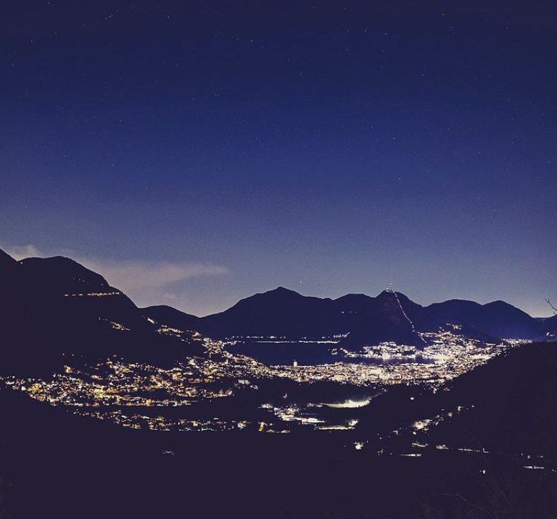Una vista di una città di notte con le montagne sullo sfondo