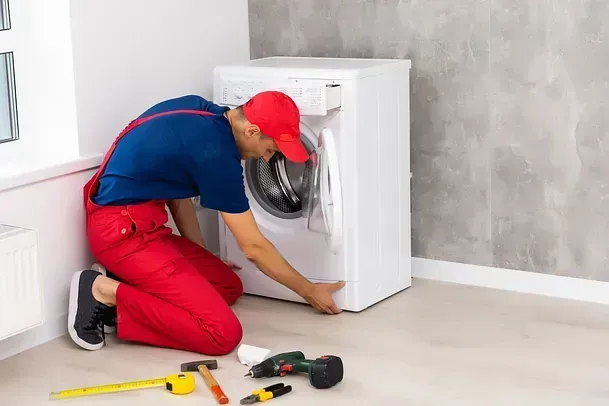 Un hombre está arreglando una lavadora en una habitación.