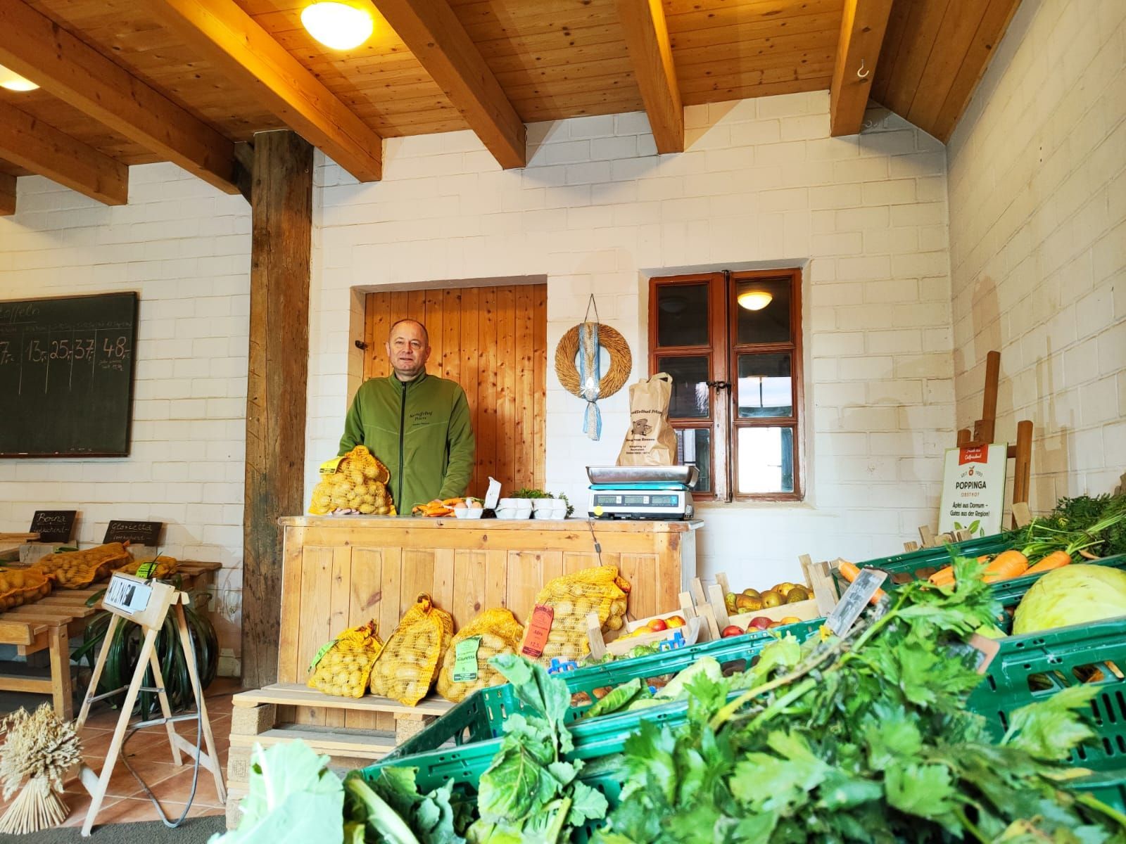 Ein Mann steht hinter einer Theke voller Gemüse.