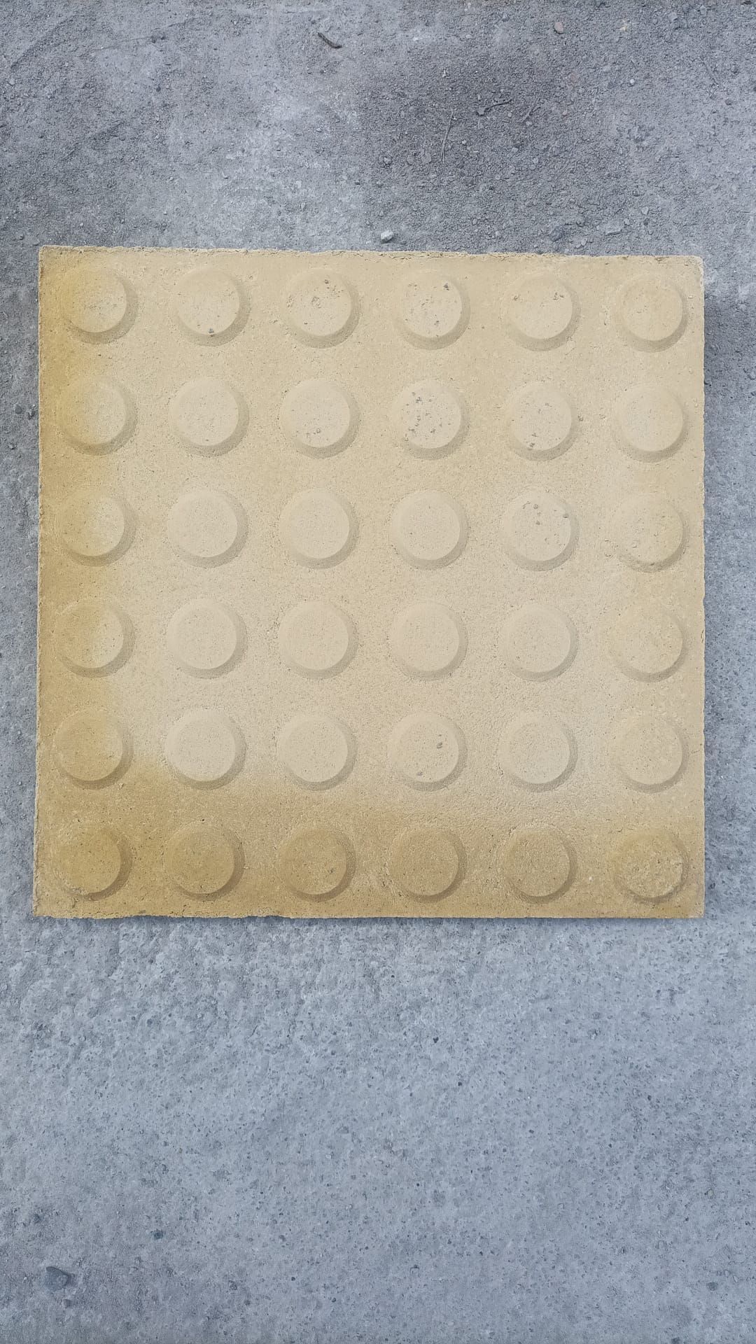 Pila de paneles rectangulares de color gris claro envueltos en plástico transparente sobre una paleta de madera.