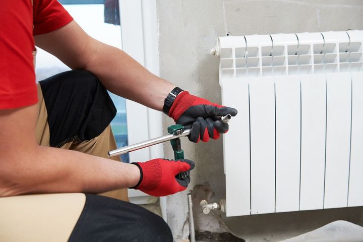 Plombier réparant un radiateur.