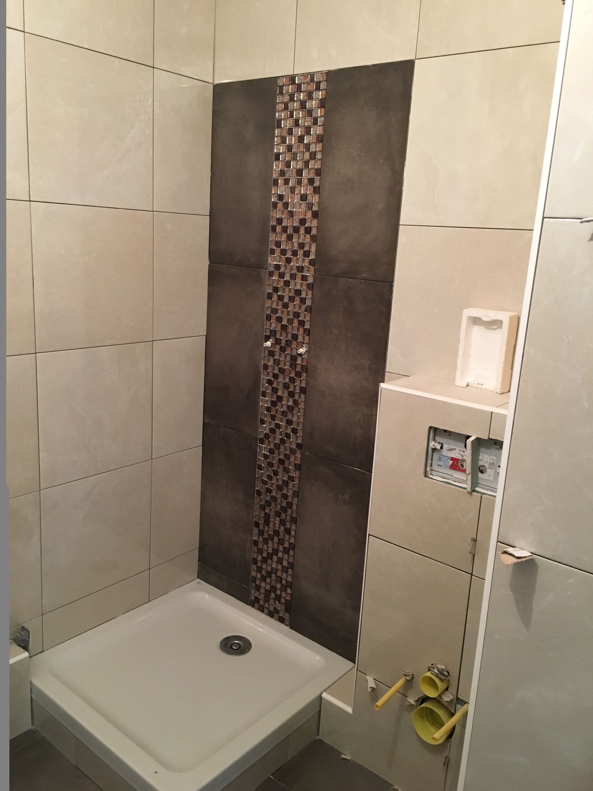 Cabine de douche avec carrelage beige et marron, petite bande de mosaïque et receveur de douche blanc