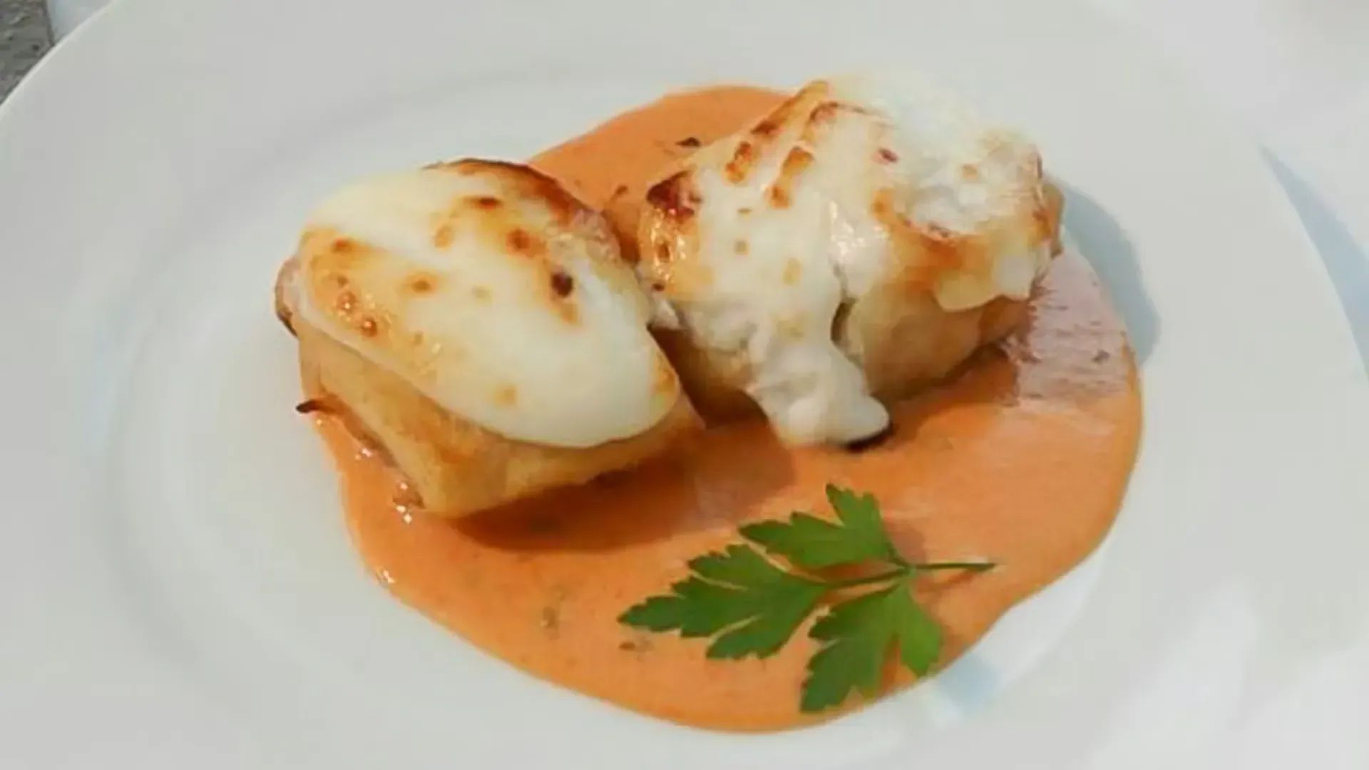 Conchas de pasta rellenas al horno con salsa cremosa de naranja y perejil en un plato blanco.