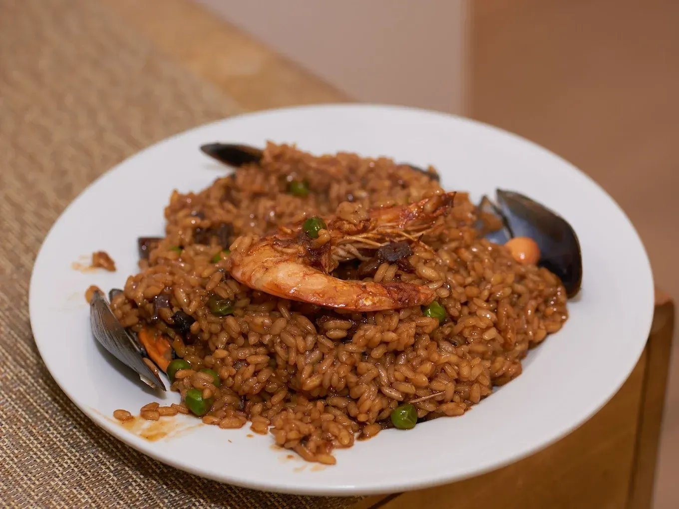 Plato de arroz oscuro con camarones en un plato blanco.