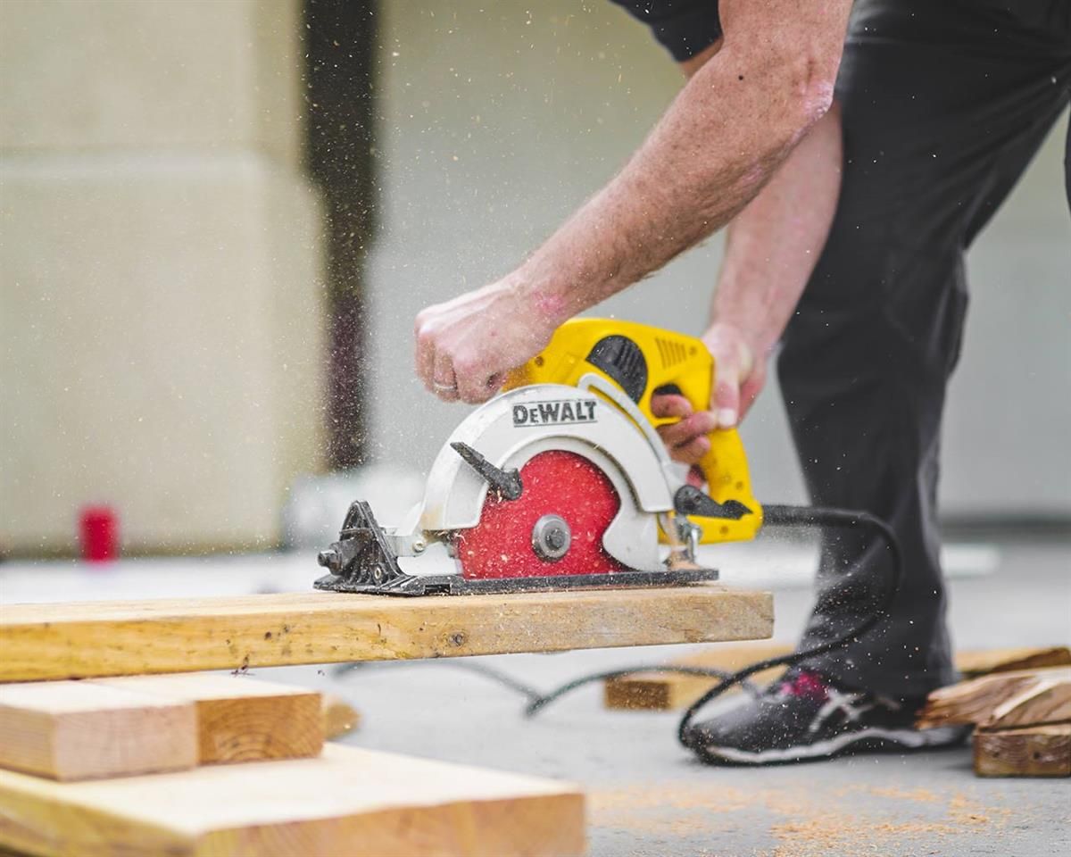 Ein Mann schneidet mit einer Dewalt-Kreissäge ein Stück Holz