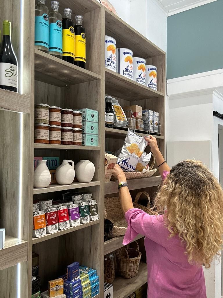 Una mujer está alcanzando una bolsa de patatas fritas en una tienda.