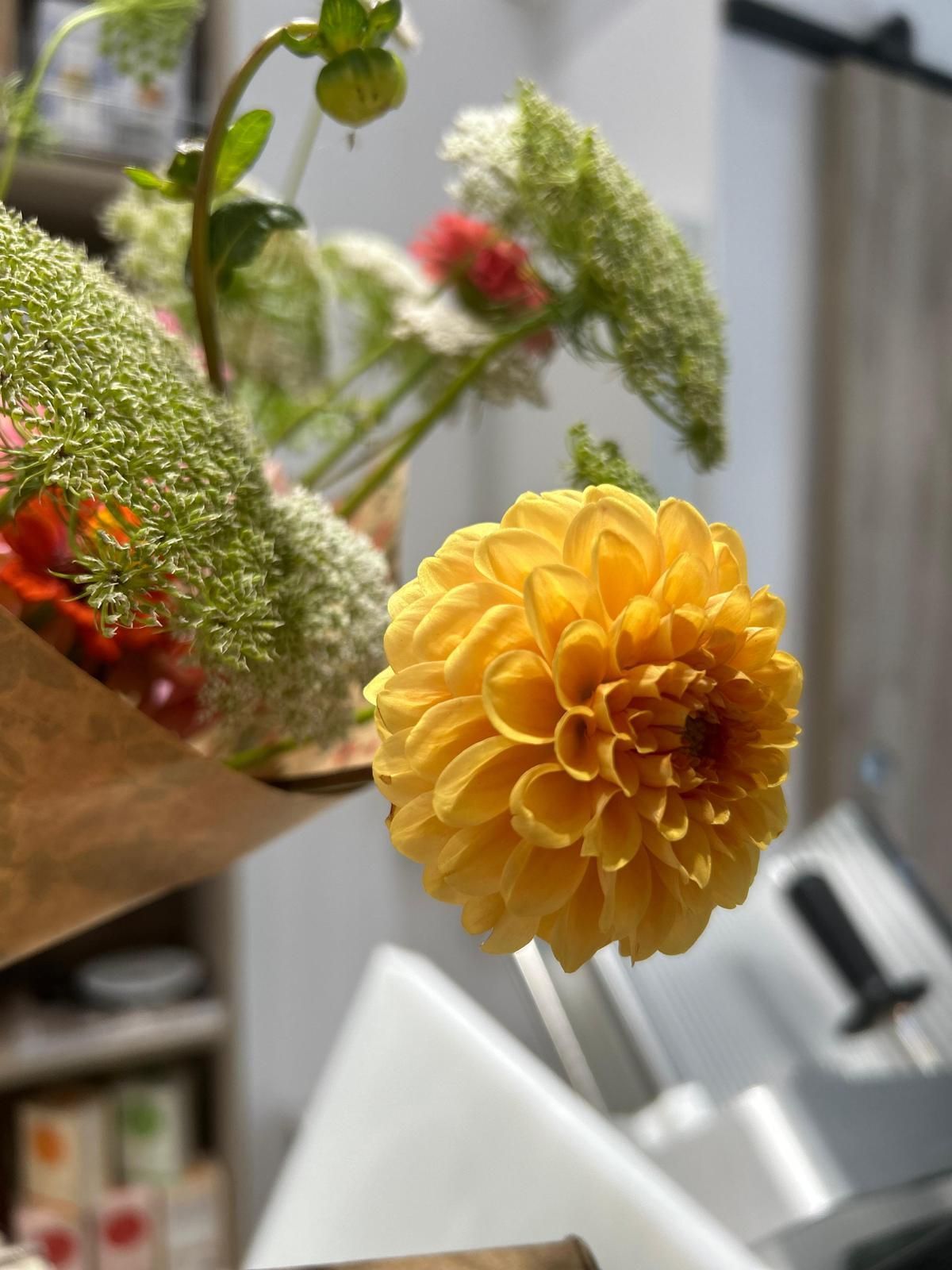 Un primer plano de una flor amarilla colocada encima de una mesa.
