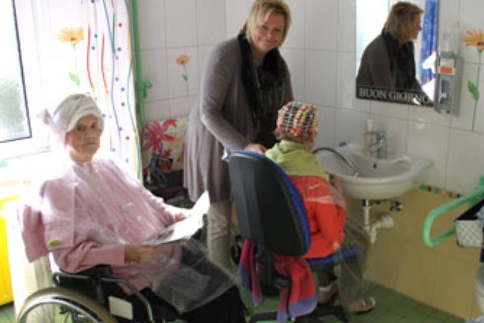 Pflegekraft mit älteren Damen bei der Haarpflege