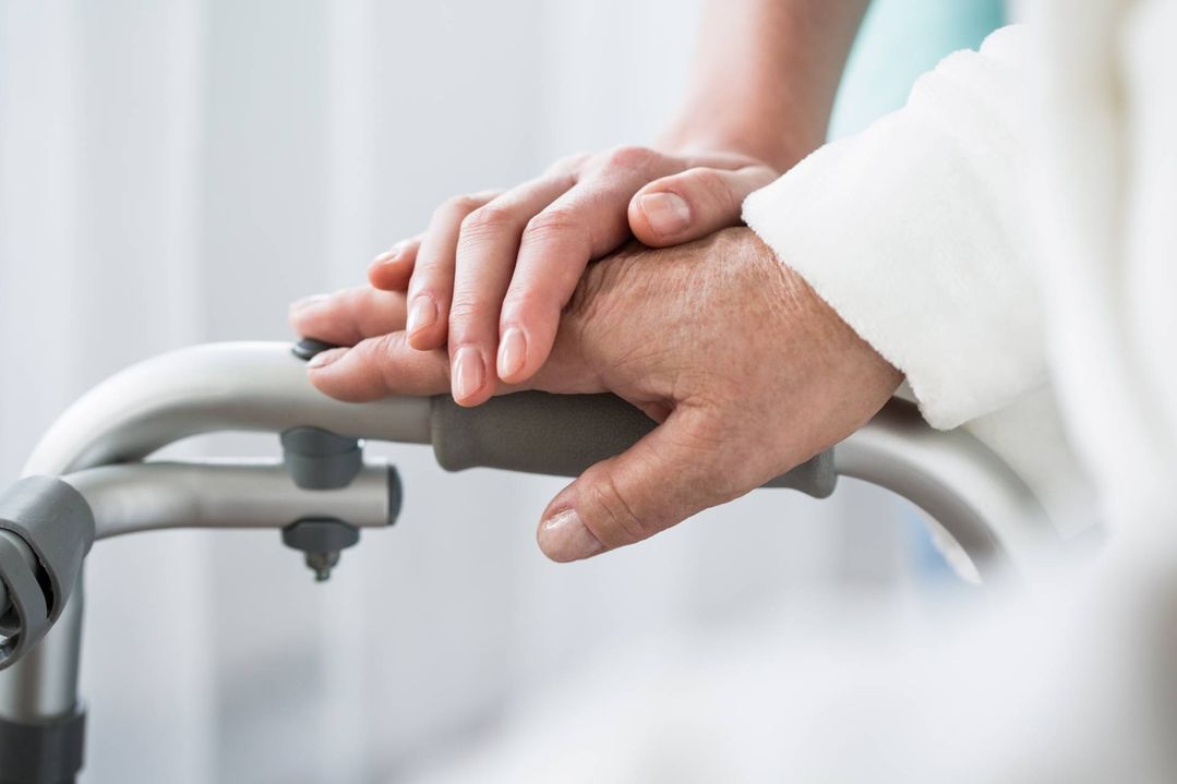 Pflegekraft hält eine Hand eines Patienten