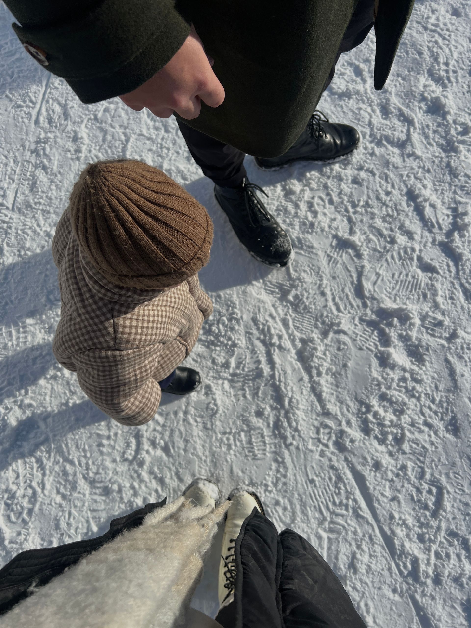 Persona caminando con un niño con ropa de invierno sobre una superficie nevada. Vista desde arriba.