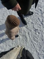 Persona caminando con un niño con ropa de invierno sobre una superficie nevada. Vista desde arriba.
