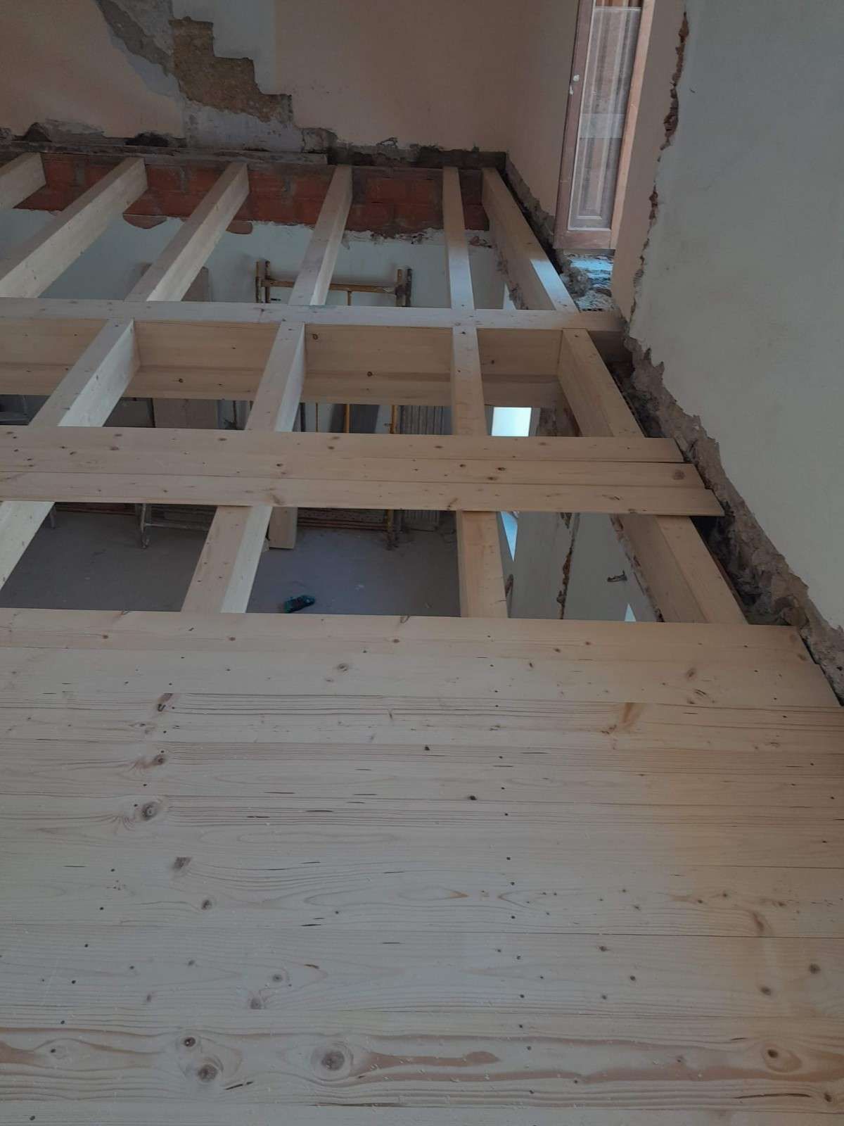 Puerta y ventana de cristal con marco de madera que dan a una habitación luminosa con armarios empotrados de madera.