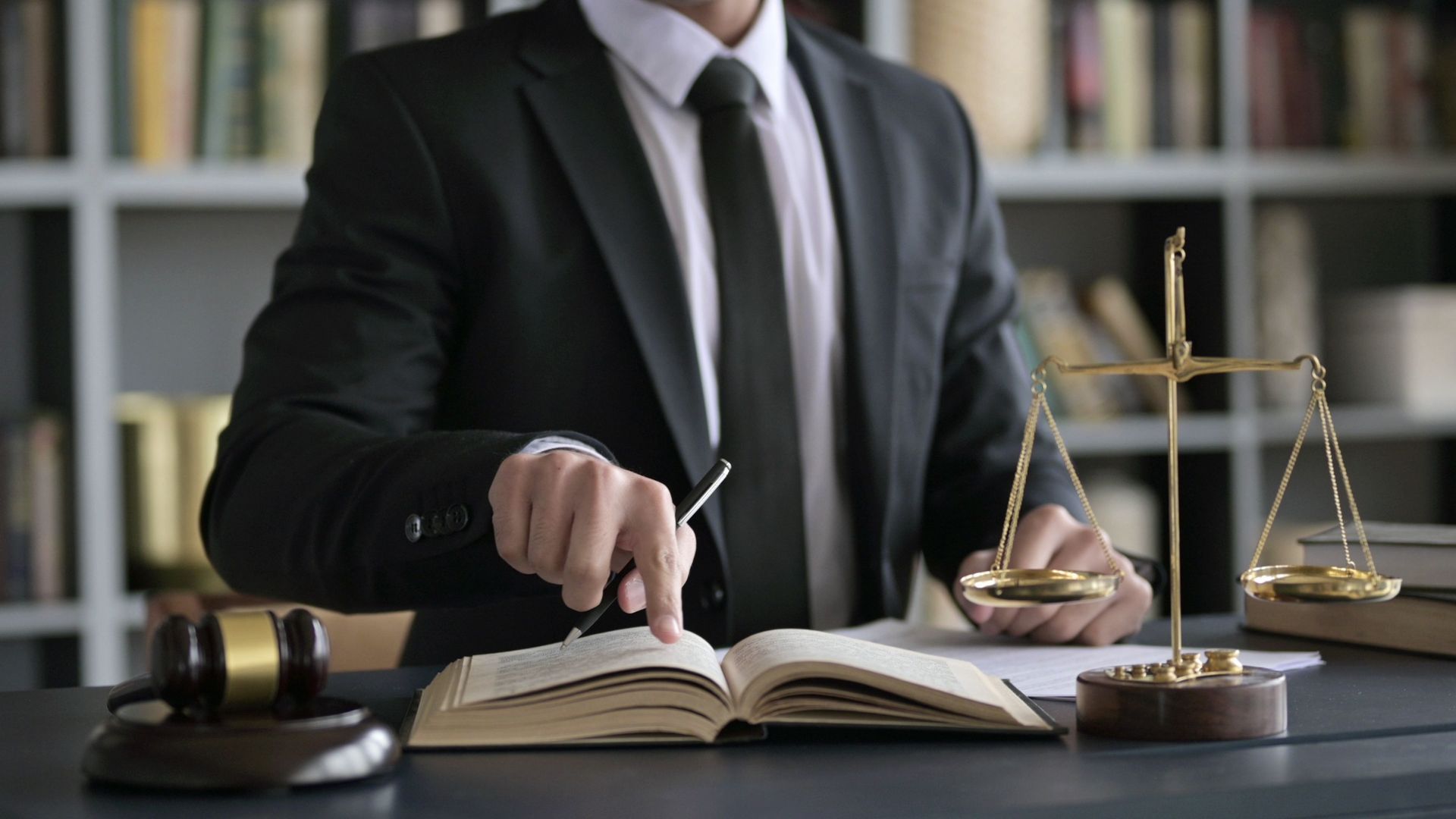 Un abogado está sentado en un escritorio con un libro y una balanza de justicia.
