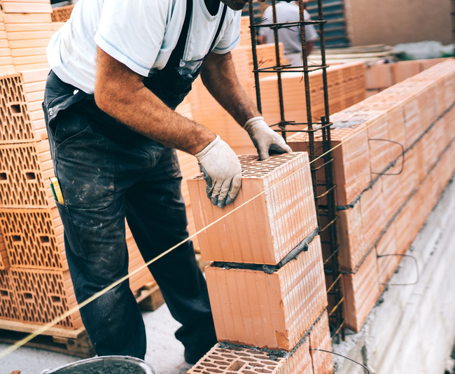 Ouvrier empilant des briques sur une palette sur un chantier de construction