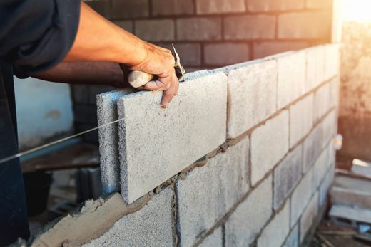 Pose d'un bloc de béton dans un mur de briques partiellement construit