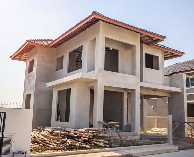 Maison à deux étages en construction, avec des murs gris inachevés