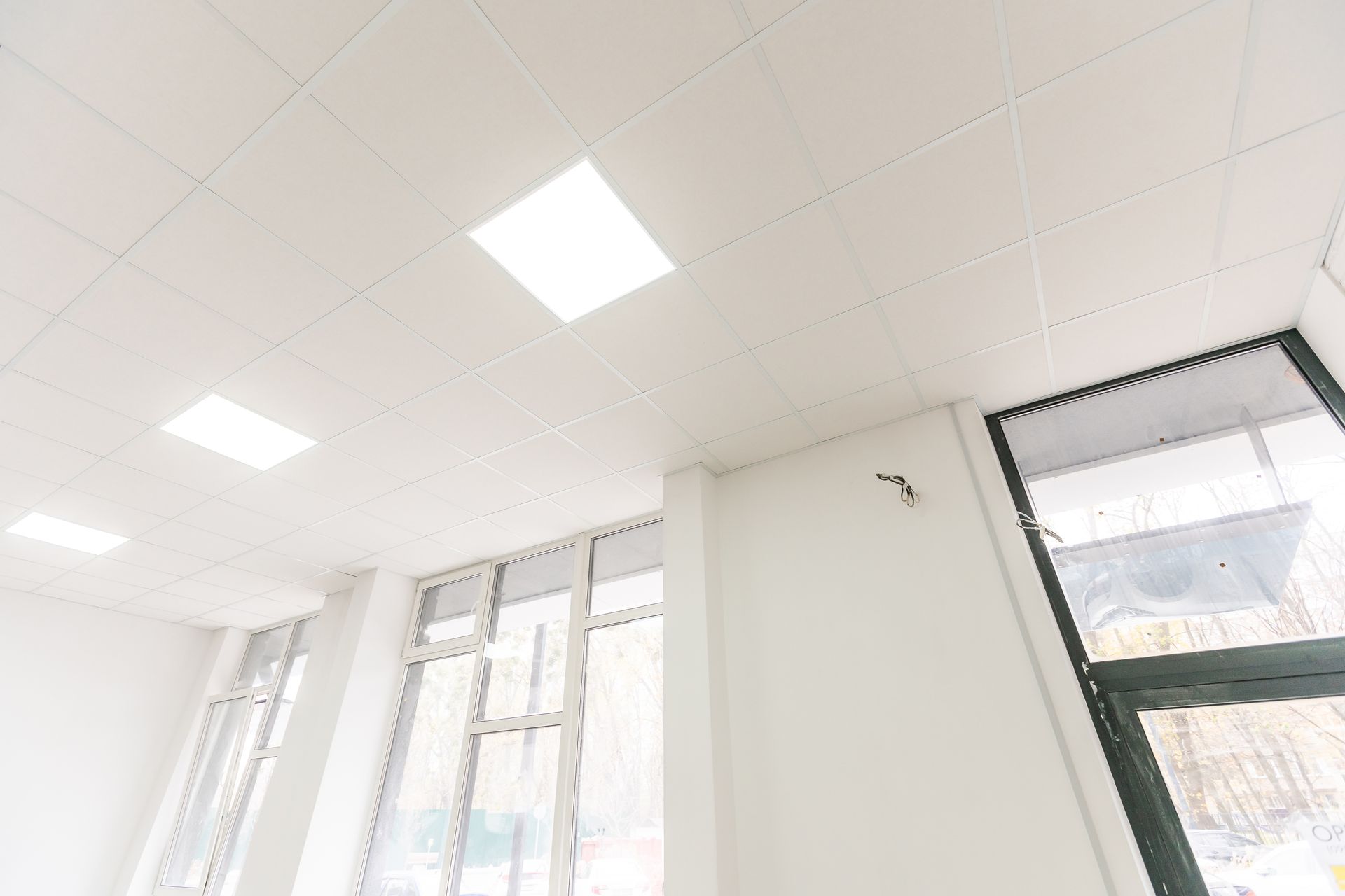 Plafond blanc lumineux avec spots encastrés et grandes fenêtres le long du mur