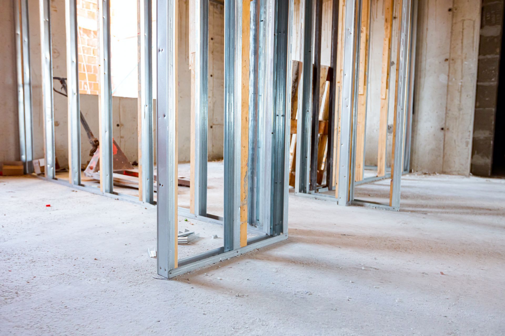 Intérieur en cours de construction avec murs à ossature, montants apparents et sol en béton brut