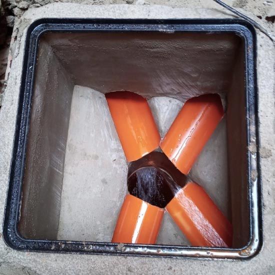 Una caja de hormigón de la que salen tubos de color naranja.