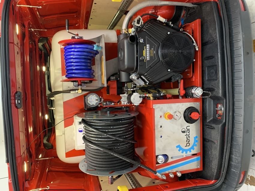 Una camioneta roja con una máquina en la parte trasera.