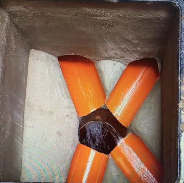 Cuatro tubos naranjas están conectados entre sí en una caja.