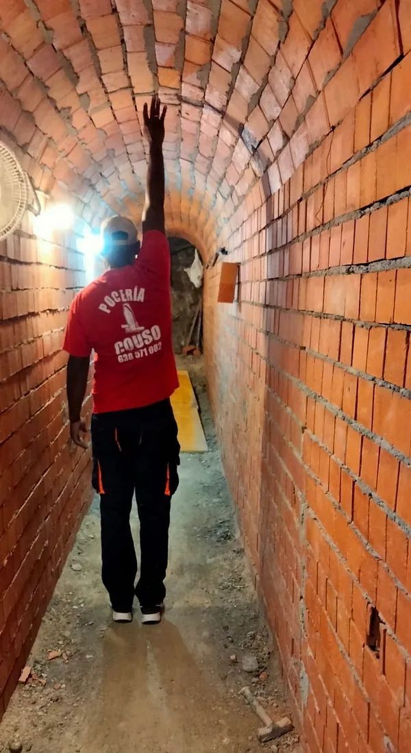 Un hombre con una camisa roja está parado en un túnel.