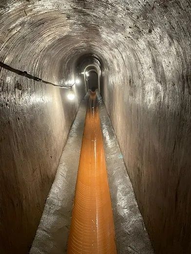Un túnel con un gran tubo naranja que lo atraviesa.