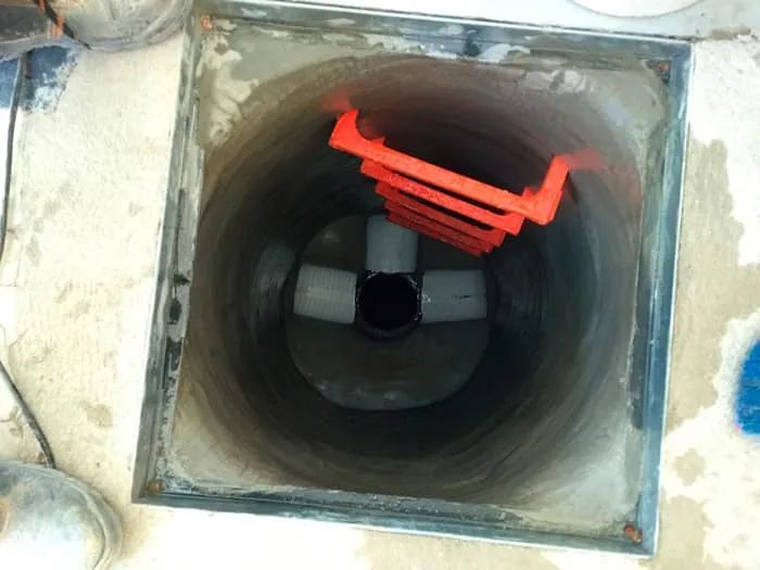 Una tapa de alcantarilla con una escalera roja en su interior.