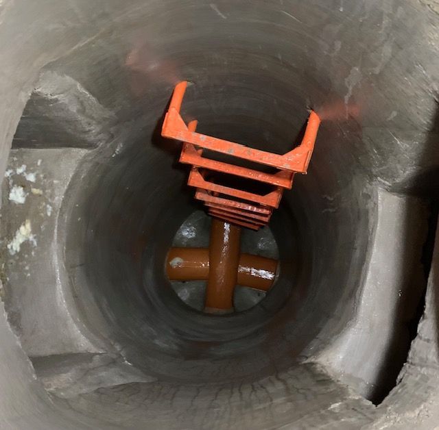 Un agujero en el suelo con un objeto naranja dentro.