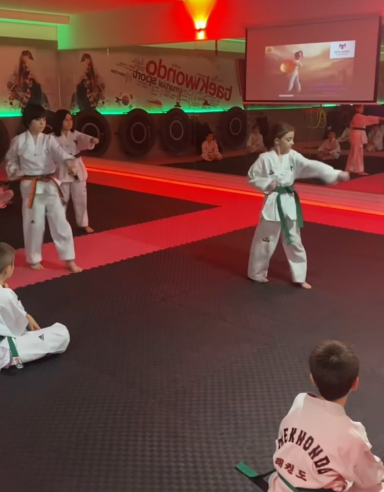 Dos artistas marciales con uniformes blancos y negros se enfrentan en una postura de combate concentrada.