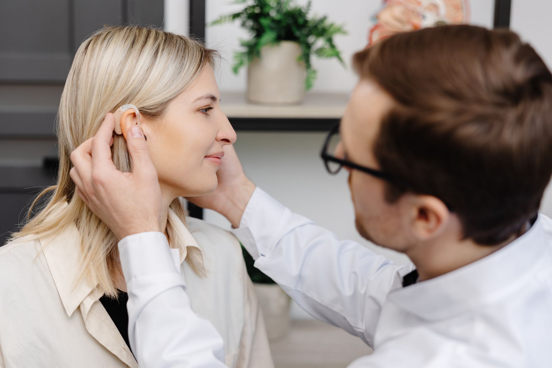 Femme qui se fait ajuster son appareil auditif par un médecin