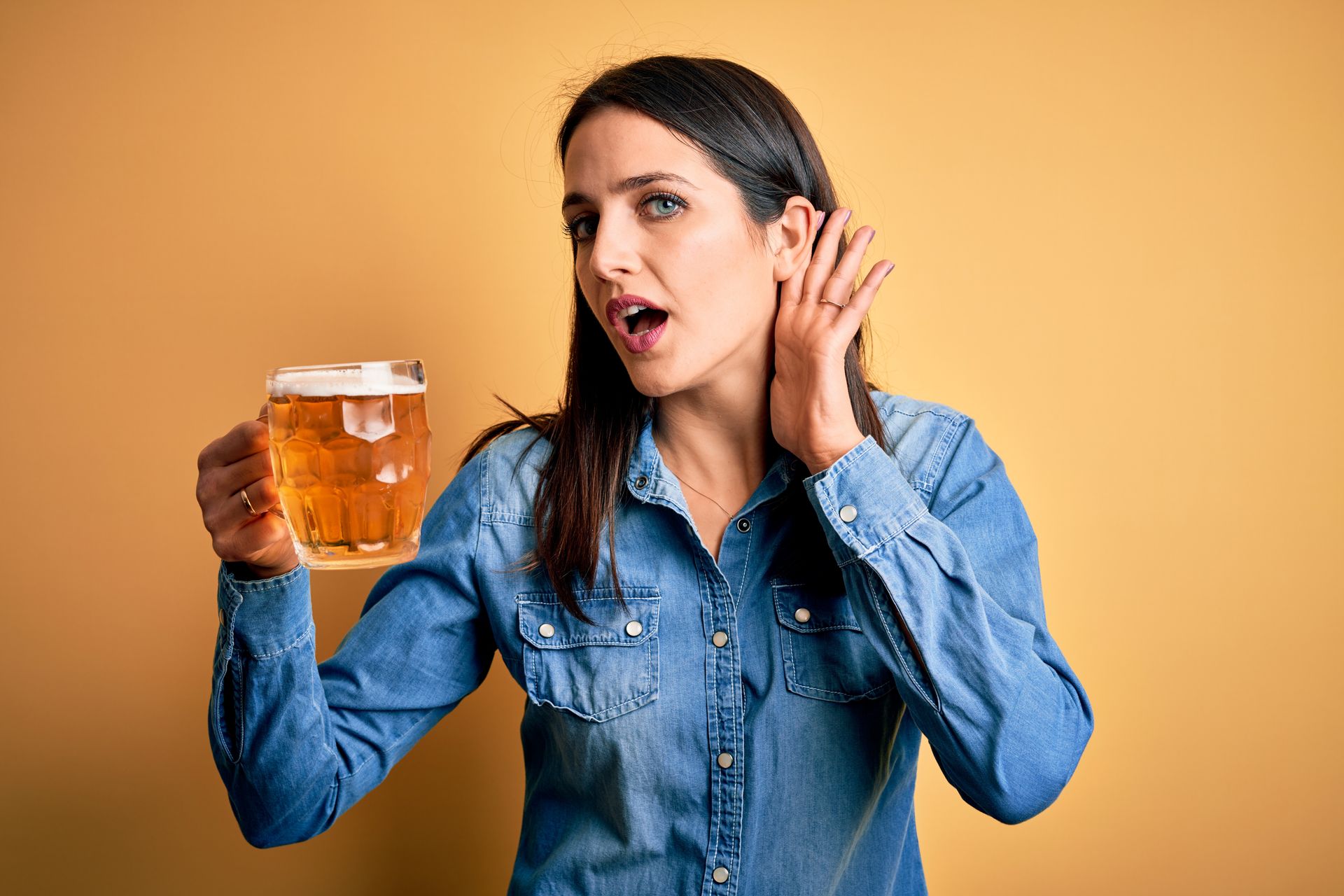 Une femme tient une bière pression en tendant l'oreille