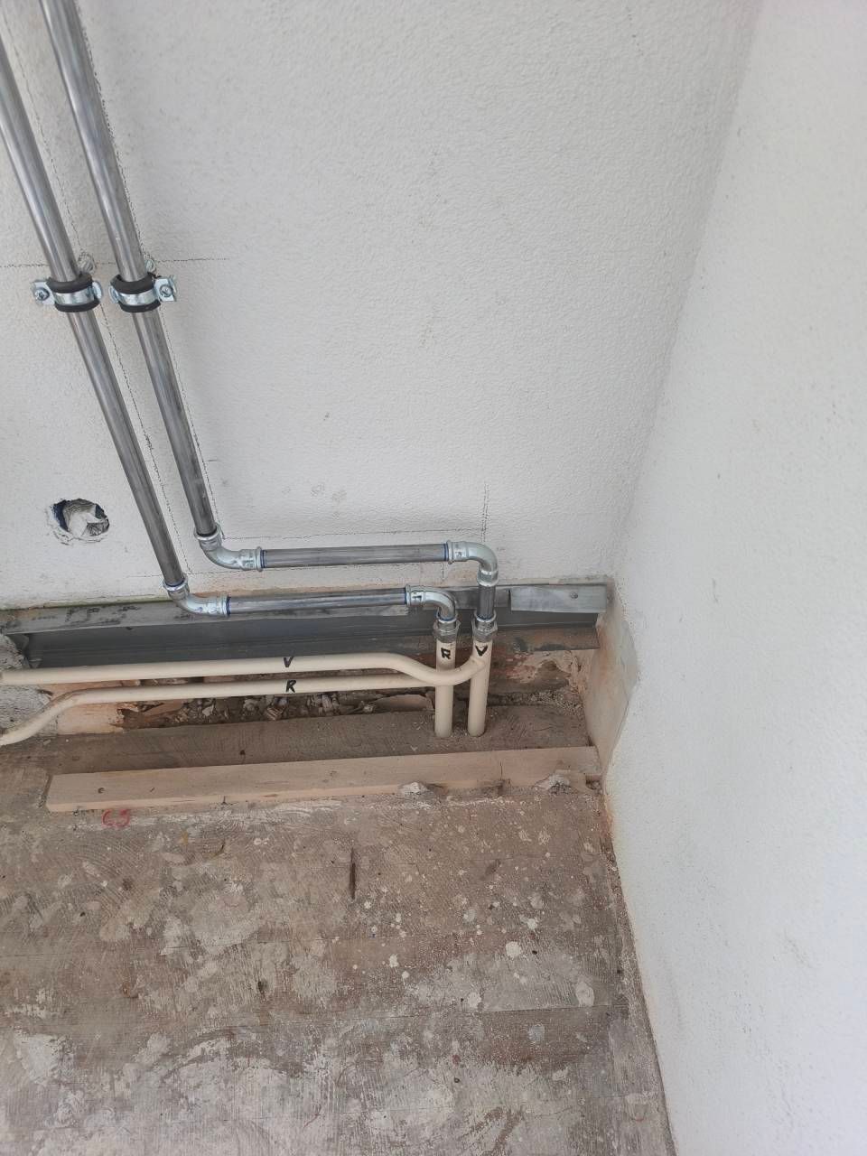 Ein Techniker in rotkariertem Hemd und blauem Overall inspiziert mit Werkzeugen einen wandmontierten Heizkessel.