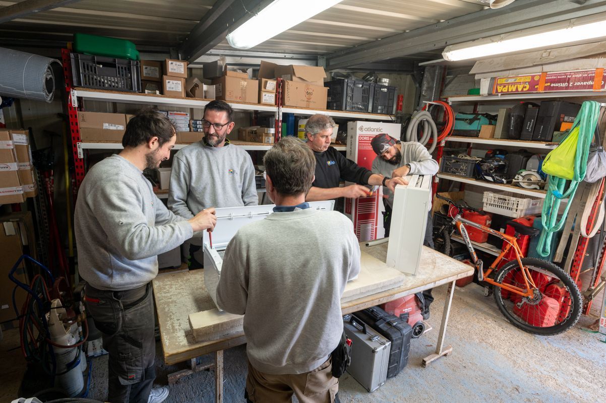 L'équipe de l'entreprise rassemblée dans l'atelier, autour d’un établi couvert d’outils et de matériaux.