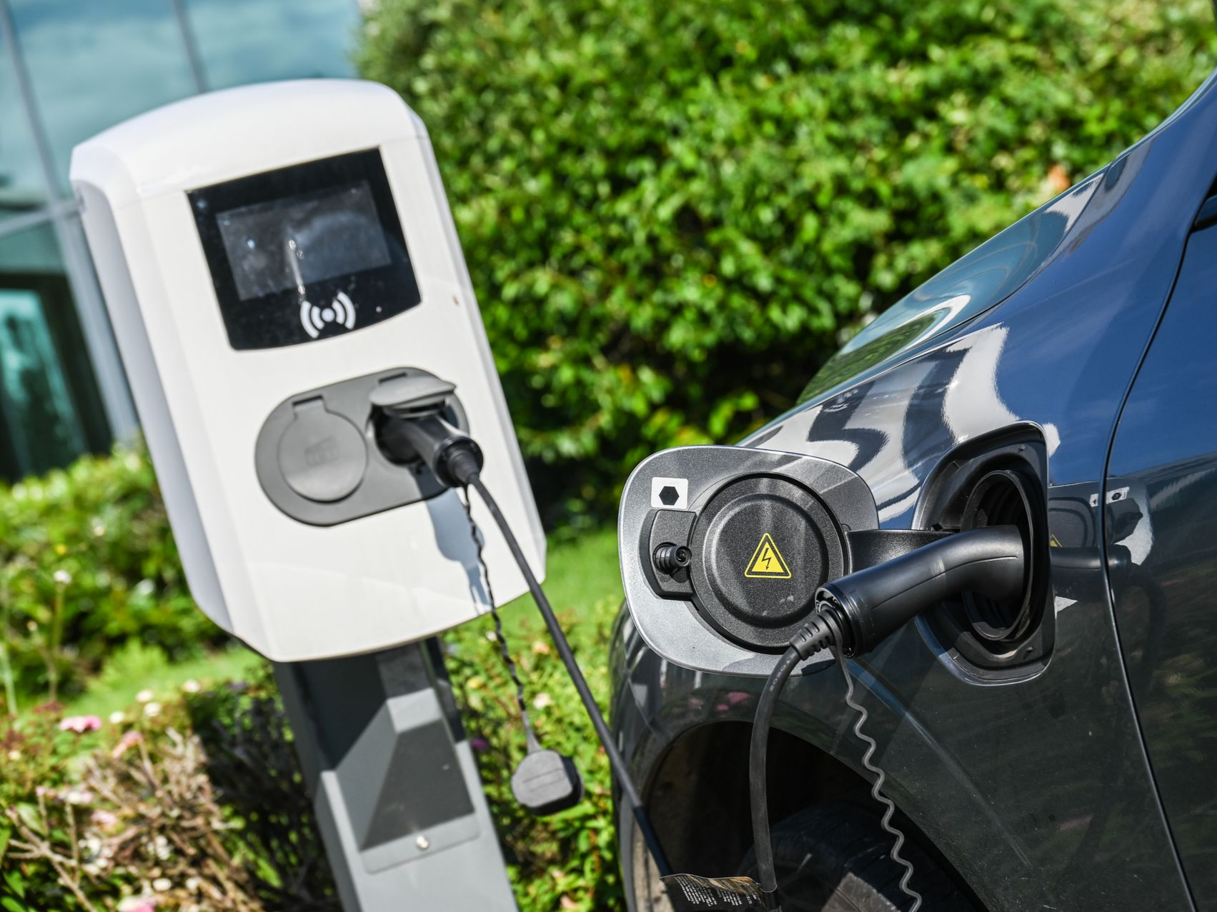 Recharge d’une voiture électrique sur une borne publique, avec la prise branchée sur le port avant du véhicule.