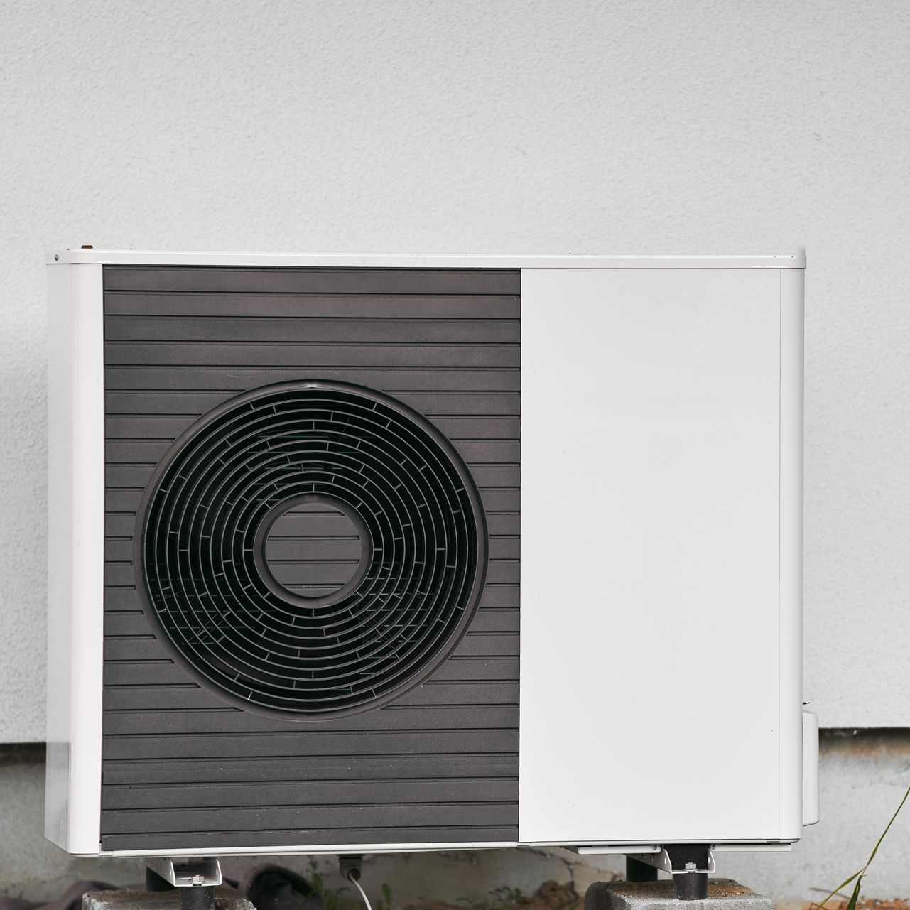 Unité de climatisation extérieure blanche avec un grand ventilateur noir sur le côté gauche.