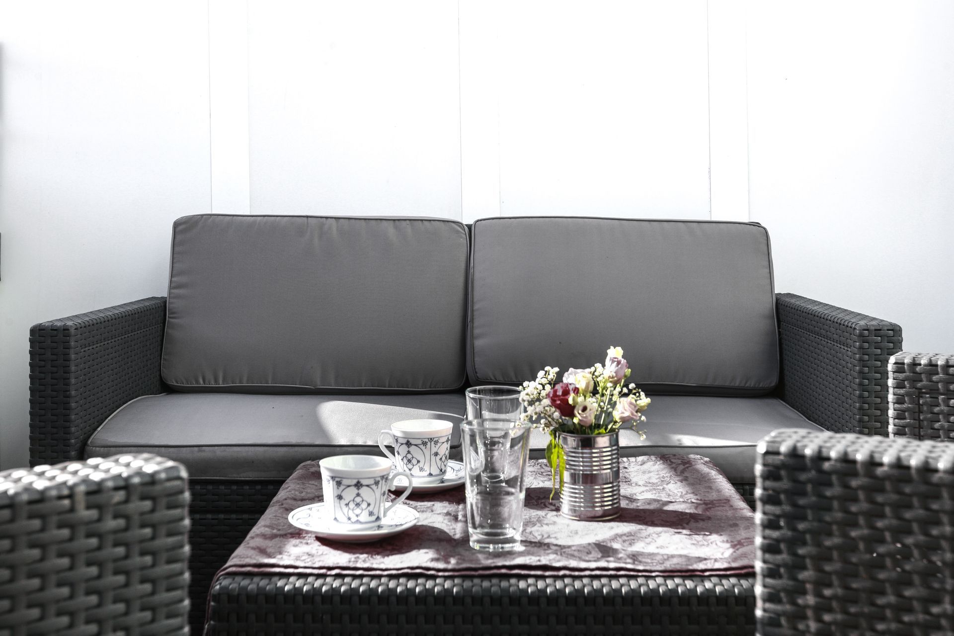 A living room with a couch , chairs , a table and a vase of flowers.