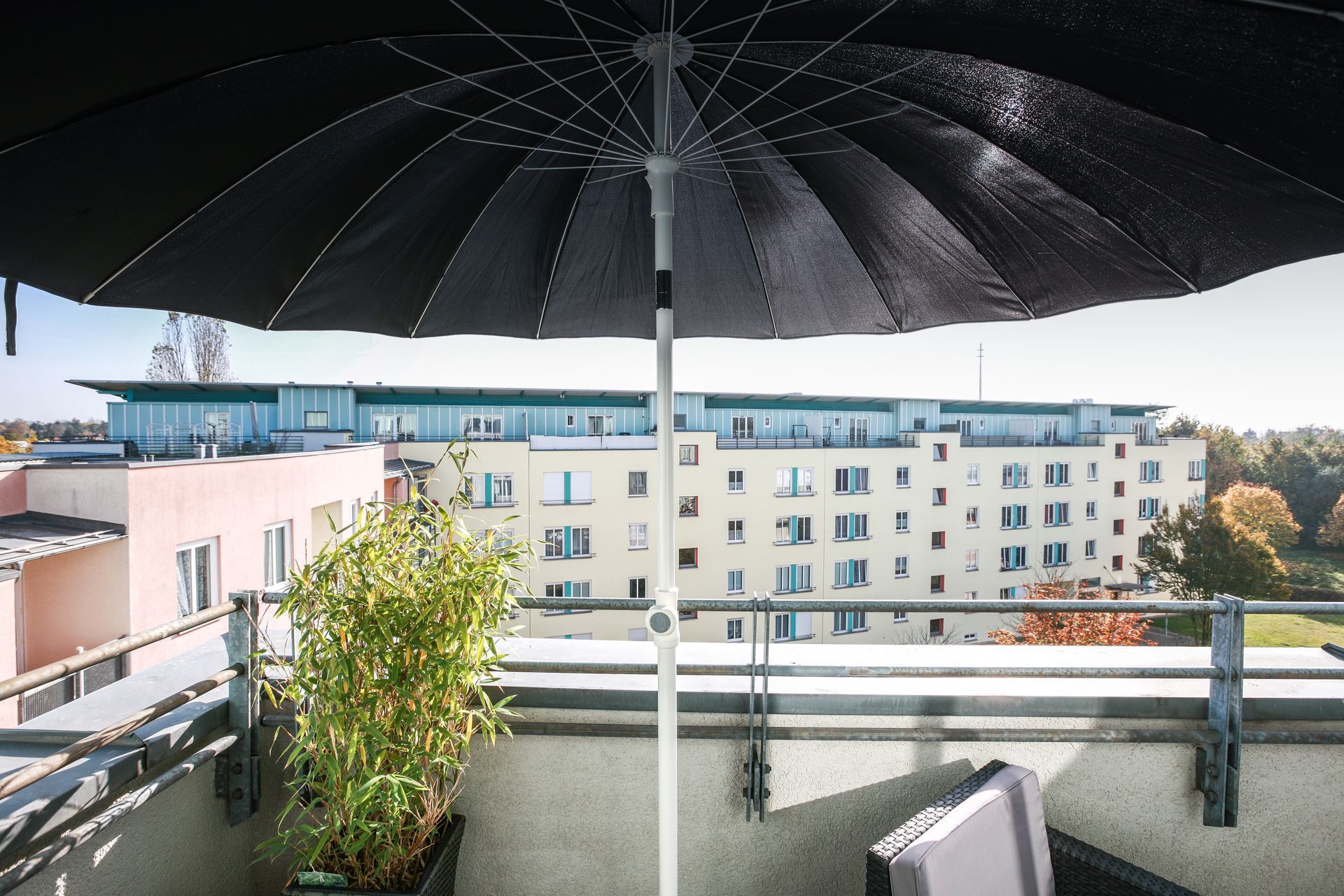 A black umbrella is sitting on a balcony overlooking a city