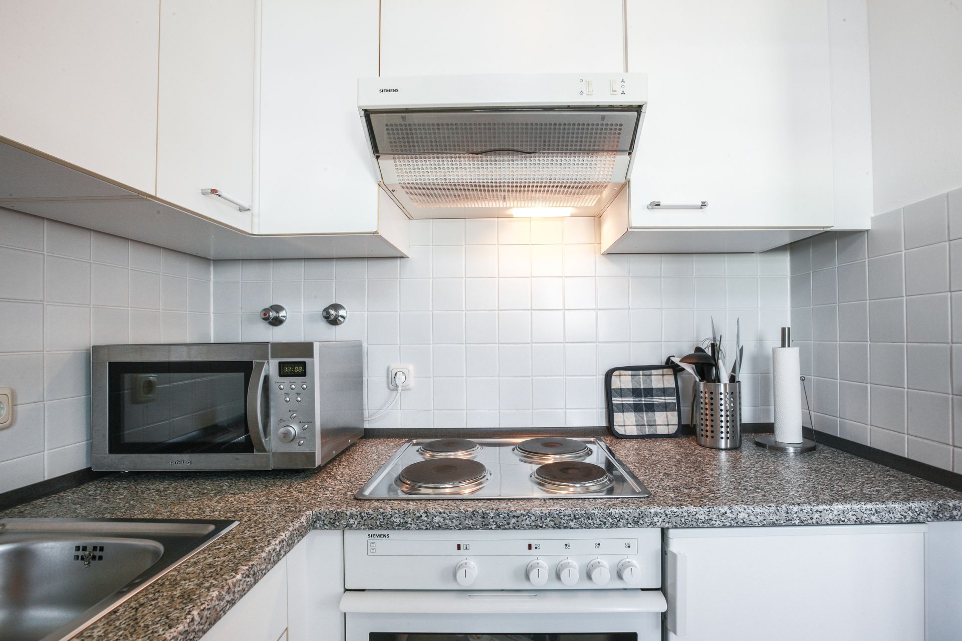 A kitchen with a stove , microwave , sink and hood.