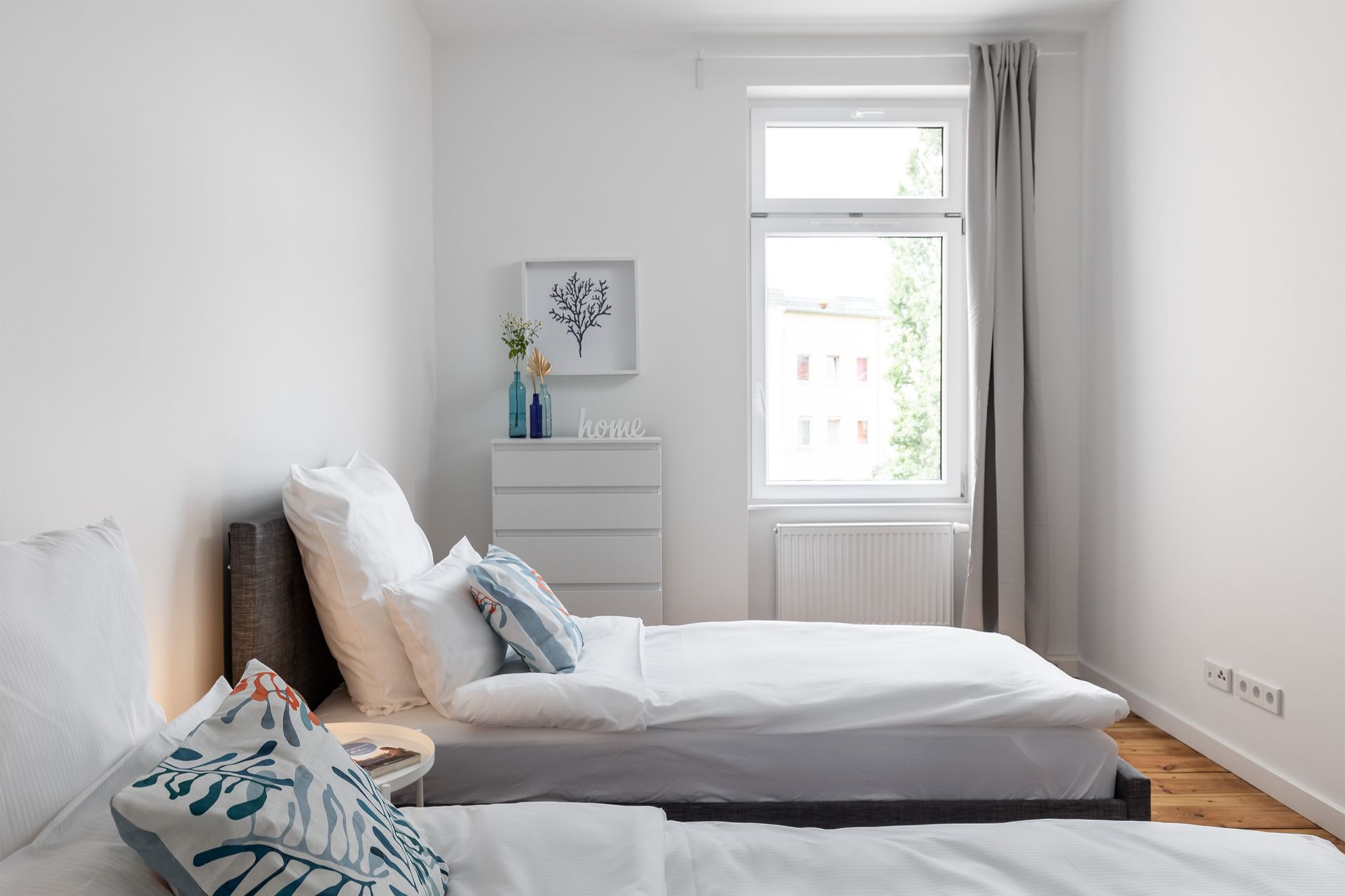 A bedroom with two beds and a window.