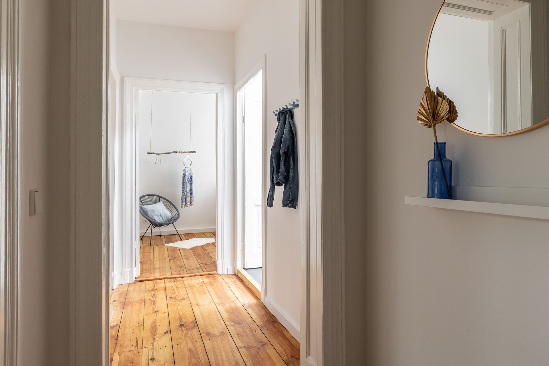 A hallway with wooden floors and a mirror on the wall.